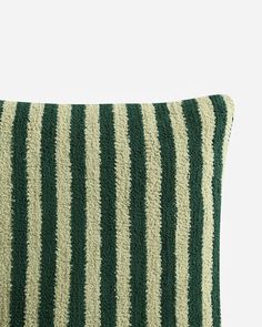 a green and white striped pillow on a white surface with black stripes in the middle