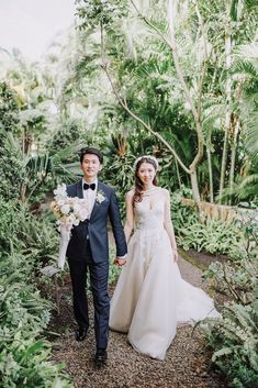 a bride and groom are walking through the jungle