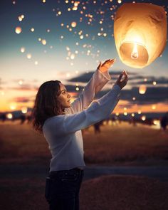 a woman holding up a lantern in the air with other balloons floating above her and text that reads explore