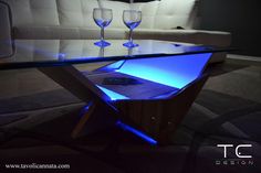 a glass table with some wine glasses on it and a couch in the back ground