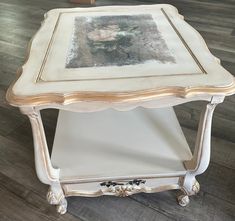 an old white table with a painting on it's top and some wood floors