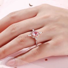 a woman's hand with a ring on her finger and a pink diamond in the middle