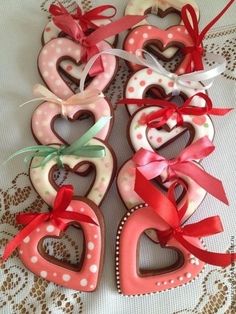 heart shaped cookies with ribbons tied around them on a lace doily covered tablecloth