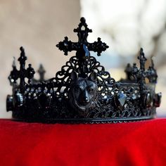 a black tiara with an animal head on the front and sides, sitting on a red cloth