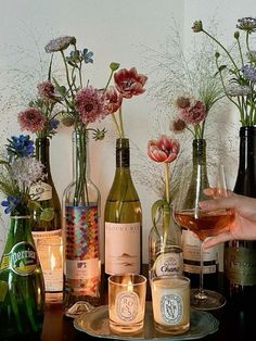 a person holding a wine glass in front of several bottles and glasses on a table