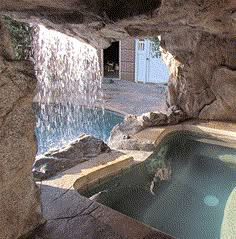 an indoor swimming pool with waterfall and rock walls