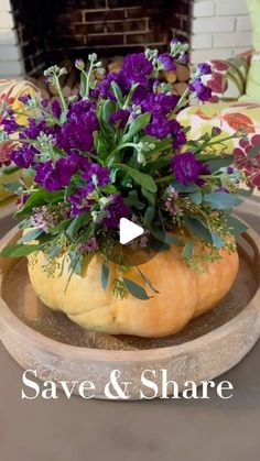 a vase with purple flowers in it sitting on a table next to a fire place