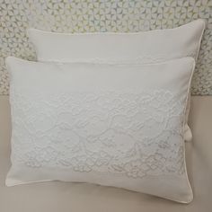 two white pillows sitting on top of a bed next to a wallpapered headboard