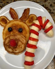 a plate topped with pancakes and fruit shaped like a reindeer face next to a banana split