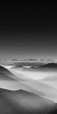 black and white photo of mountains with fog in the air, taken from an airplane