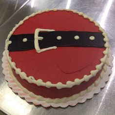 a red cake with white frosting and a black belt on it's side