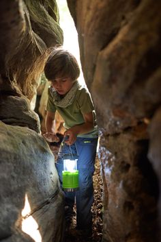 A boy is using a lantern to explore a cave. Night Hiking, Led Camping Lantern, Camping Lanterns, Beach Toys, Nature Kids