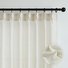 a white curtain hanging on a black rod with a round object in front of it