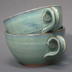 two cups are sitting side by side on a gray surface with one cup in the middle