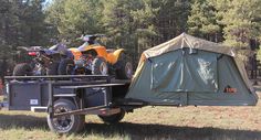 two atvs are parked in the back of a trailer with a tent on it