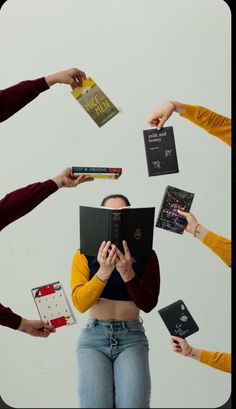 a group of people holding books in the air with their hands on top of each other