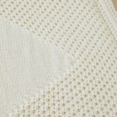 a white knitted blanket laying on top of a wooden table