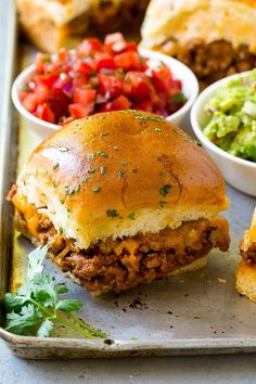 the sandwich is cut in half and served with guacamole, salsa, and tortilla chips