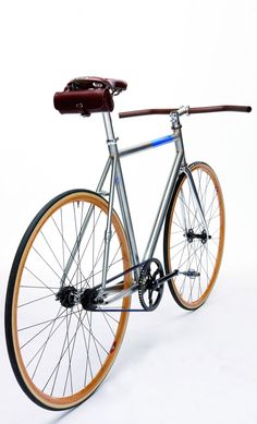 a silver bicycle with orange rims and a brown saddle on the front wheel, against a white background