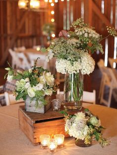 flowers in vases sitting on top of a wooden box at a wedding reception table