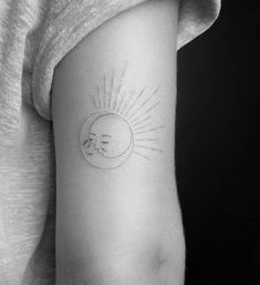 a small sun and moon tattoo on the left side of the arm, which has a line drawing of a sleeping baby