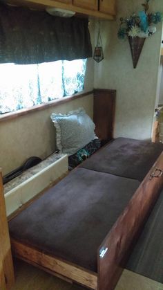 two twin beds in a small room with wood flooring and wooden cabinetry on the walls