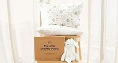 a white stuffed animal sitting on top of a box next to pillows and pillow cases