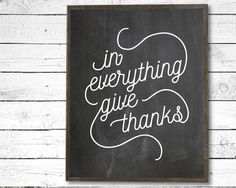 a chalkboard with the words in everything give thanks written on it against a white wooden background