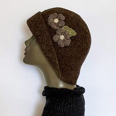 "This felted wool hat is the hat with an attitude   A unique and captivating hat resembling those hats of days gone by, this hat is approximately 22\" in circumference and can also be stretched if necessary.  The two felted flowers and leaf, which are sewn on, accentuate and add dimension to the Brown hat.  This style of hat can be worn in many different ways, totally up to you - there is no wrong way or right way - just the way you choose to wear it! The hat is crocheted by hand with quality wo Handmade Fitted Brown Hat, Adjustable Felt Cap, Winter Wool Mini Hat With Curved Brim, Brimmed Felt Hats One Size, Wool Hats With Short Brim, Handmade Wool Hats One Size Fits Most, Brown Cloche Hat With Short Brim, Handmade Brown Cloche Hat With Wide Brim, Handmade Brown Hat As A Gift