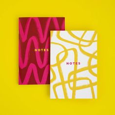 two notebooks sitting next to each other on a yellow surface with the words notes written in red