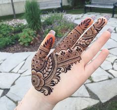 a person's hand with henna tattoos on it and some flowers in the background