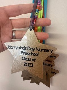 someone is holding three star shaped medals in their hand, with the words everyone's day nursery preschool class of 2013 written on them