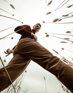 a man standing in tall grass with his hands on his hips and looking up at the sky