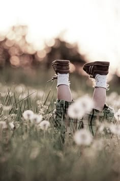 the legs of two people in plaid socks and mittens are standing in tall grass