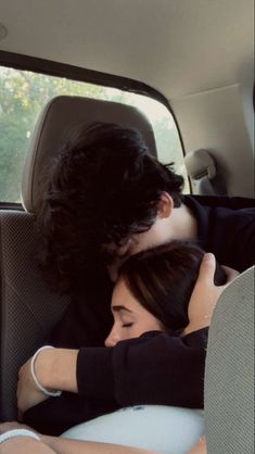 a man and woman are sitting in the back seat of a car, hugging each other