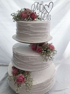 three tiered wedding cake with pink roses and baby's breath on the top