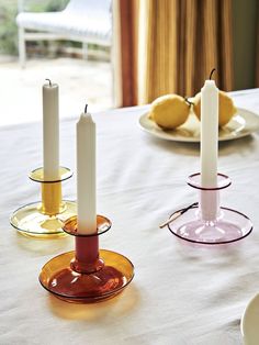 three candles sitting on top of a table next to plates with lemons in the background