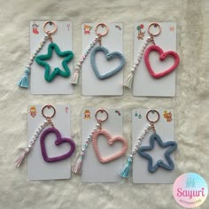 six keychains with different colors and designs on them, all in the shape of hearts