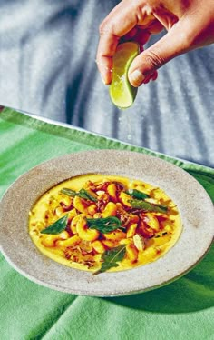 a person is sprinkling something into a bowl of food on a green table cloth