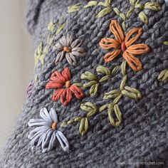 a close up of a pillow with flowers and leaves on it's back side