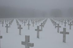 many crosses are covered in snow on a cold winter's day at the cemetary