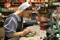 a woman in a shop working on some crafting supplies with scissors and other items behind her