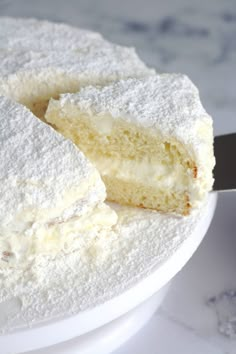 a white cake with powdered sugar on top is cut in half and sits on a plate