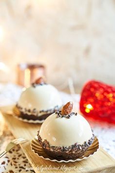 two desserts sitting on top of a wooden cutting board next to a red candle