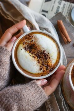 a person holding a cup of coffee with cinnamon sprinkles