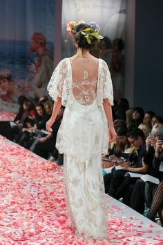 the back of a woman's dress with flowers on it and petals scattered all over