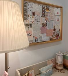 a desk with a lamp and pictures on the wall above it, along with other items