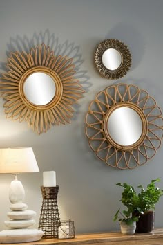 three circular mirrors mounted on the wall above a table with a lamp and potted plant