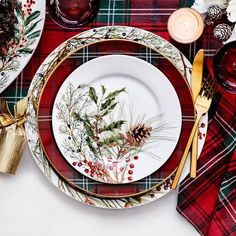 the table is set for christmas dinner with plaid napkins