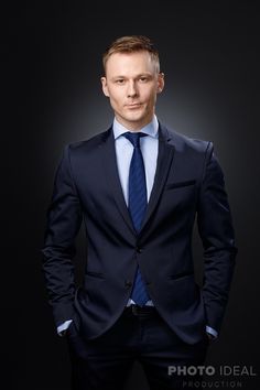 a man in a suit and tie is posing for a photo with his hands in his pockets